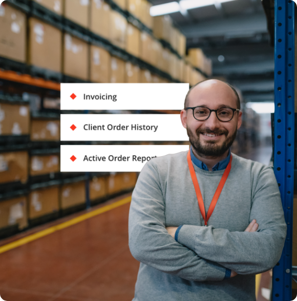 An individual with crossed arms wearing a gray sweater and a red lanyard standing in a warehouse with shelves stocked with brown cardboard boxes in the background. In the upper left corner, there is a digital overlay with the text "Invoicing," "Client Order History," and "Active Order Report," each accompanied by a red diamond-shaped bullet point.